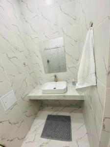 a white bathroom with a sink and a mirror at Жк Арман двухкомнатная квартира в центре города/ Zhk Arman one-bedroom apartment in the city center in Atyraū