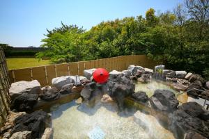 un ombrellone rosso in una piscina d'acqua con rocce di Ooedo Onsen Monogatari Premium Hotel Sokan a Matsushima