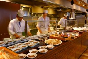a group of chefs preparing food in a kitchen at Ooedo Onsen Monogatari Premium Hotel Sokan in Matsushima
