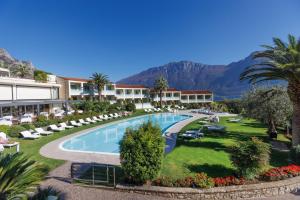 リモーネ・スル・ガルダにあるパーク ホテル インペリアルのスイミングプールと山々を背景に望むリゾート
