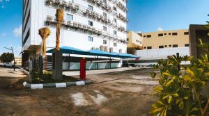 a building with a blue umbrella and palm trees in a parking lot at DIFFERENT HOTEL in Tabuk