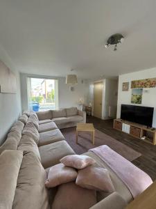 a living room with a large couch and a television at Great House + air conditioning + free car parking in Manchester