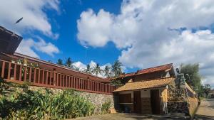 um edifício com um telhado vermelho e um céu nublado em RedDoorz Syariah at Banyu Asem Banyuwangi em Banyuwangi