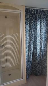 a glass shower door with a blue and white curtain at Bienvenue chez Anaïs ! in Biville-sur-Mer