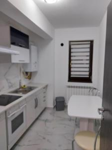 een keuken met witte kasten, een wastafel en een raam bij Bya Brown Residence in Valea Lupului