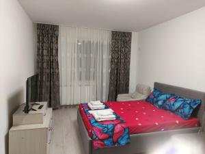 a small bedroom with a red bed and a television at Bya Brown Residence in Valea Lupului +2 photos