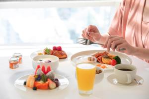 Eine Frau, die an einem Tisch mit einem Teller Essen sitzt. in der Unterkunft Sofitel Haikou in Haikou