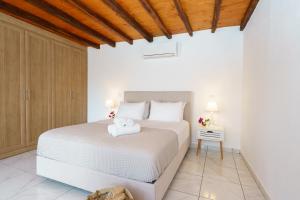 Villa Maria - Hydra Dream Houses في هيدرا: غرفة نوم بسرير ابيض وسقف خشبي
