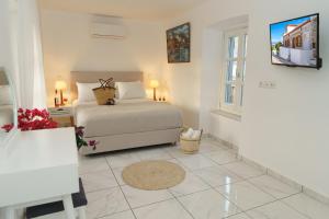 a white bedroom with a bed and a window at Villa Maria - Hydra Dream Houses in Hydra