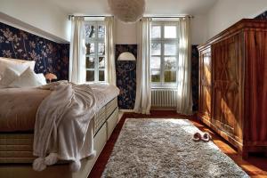 1 Schlafzimmer mit einem Bett, 2 Fenstern und einem Teppich in der Unterkunft Boutique Suites and Residences Heidelberg- Alte Zigarrenmanufaktur in Heidelberg