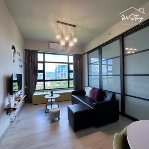 a living room with a black couch and some windows at WiStay 4-5PAX Premium Apartment KK City Center in Kota Kinabalu