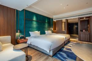 a bedroom with a large white bed and a green wall at Gao Shi Di Hot Spring Hotel Yangzhou in Yangzhou