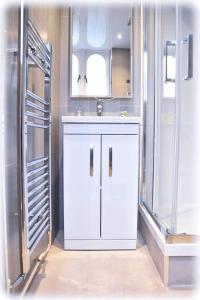 ein weißes Badezimmer mit Waschbecken und Spiegel in der Unterkunft Dobbins Inn in Carrickfergus