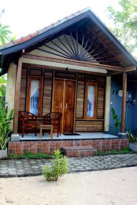 Casa pequeña con porche y puertas de madera. en Surya Home Stay, en Nusa Lembongan