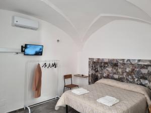 a bedroom with a bed and a chair and a tv at SUITE AGATA in Gallipoli