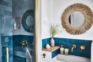 bagno con piastrelle blu, specchio e lavandino di Maison normande face à la plage d'Houlgate a Houlgate