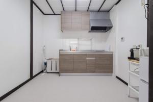 a kitchen with white walls and wooden cabinets at FTH maroon 4min to station in Azagawa
