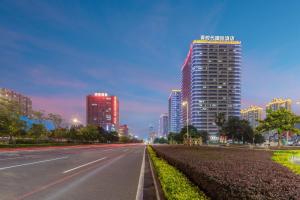 una strada di città di notte con edifici alti di Time Hotel Apartments a Dongguan