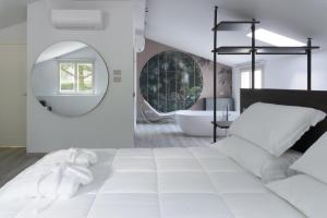 1 dormitorio con 1 cama blanca grande y espejo en Colle Serrano Relais & SPA, en Ripatransone