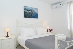 a white bedroom with a bed and a chair at Kamini - Hydra Dream Houses in Hydra