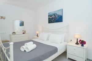 ein weißes Schlafzimmer mit einem Bett mit Handtüchern darauf in der Unterkunft Kamini - Hydra Dream Houses in Hydra