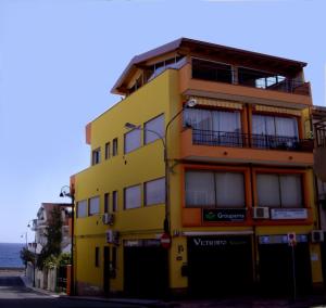 un edificio amarillo al costado de una calle en Pozzo Lazzaro Apartments, en Santa Teresa di Riva