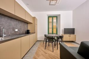 a kitchen with a table and chairs and a television at Cà del Lasco - Modern Apartments in Classic Villa in Bellano
