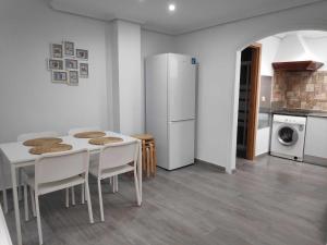 a kitchen with a white table and chairs and a refrigerator at Sonsoles Apartamentos Bahía Sur in San Fernando