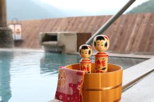 two wooden dolls sitting in a container next to a pool at Ooedo Onsen Monogatari Masuya in Osaki
