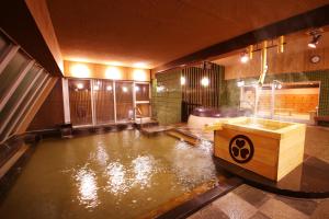 a pool of water in a room with a bath tub at Ooedo Onsen Monogatari Masuya in Osaki +7 photos