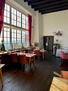 a restaurant with tables and chairs and large windows at Burghaus & Villa Kronenburg in Kronenburg