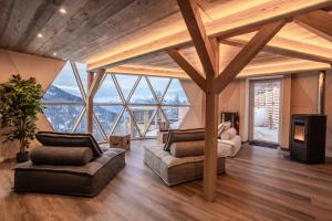 - un salon avec des canapés, une cheminée et de grandes fenêtres dans l'établissement Alpin D'Hôme Hôtel & Spa, aux Orres