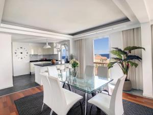 a dining room with a glass table and white chairs at Private Sunset Terrace & Ocean Cliff Pool Garden at Designer Apt by LovelyStay in Funchal