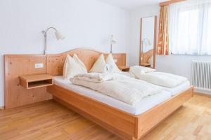 una camera da letto con un grande letto in legno con cuscini bianchi di Appartements-Restaurant Schwaiger a Tauplitz