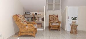 sala de estar con 2 sillas y estante para libros en Logement spacieux deux pièces à Baie Mahault, en Baie-Mahault