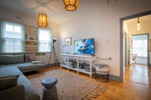ein Wohnzimmer mit einem Sofa und einem Fernseher an der Wand in der Unterkunft Cosy coastal cottage- Allwood Harbour in Kiama