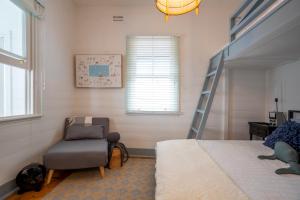 a bedroom with a bed and a chair and a ladder at Cosy coastal cottage- Allwood Harbour in Kiama