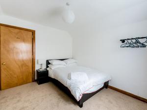 a bedroom with a white bed and a wooden door at Pass the Keys 3 Bedroom Cottage in Cupar in Cupar