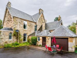 an old stone house with red chairs and a garage at Pass the Keys 3 Bedroom Cottage in Cupar in Cupar