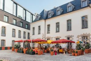 a courtyard with tables and umbrellas in front of a building at Mama Shelter Rennes in Rennes