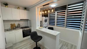 a kitchen with white cabinets and a counter with a chair at LUXURY STUDIO in Onești