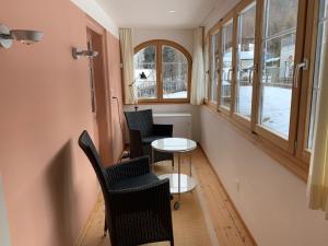 Zimmer mit Stühlen, einem Tisch und Fenstern in der Unterkunft Charmantes Alpen-Appartement in Conters, Davos-Parsenn in Conters