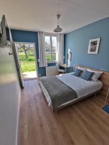 a bedroom with a large bed with blue walls and wooden floors at La mare aux petits diables in Équemauville