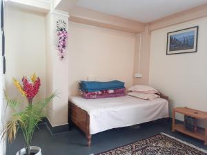 een kleine slaapkamer met een bed met witte lakens bij Neora Backpackers Hostel in Darjeeling