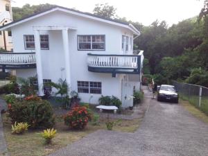 a white house with a car parked in front of it at 4Js Vacation Inc. - Luxury Studio in Gros Islet