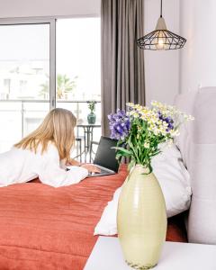 Eine Frau, die mit einem Laptop auf einem Bett liegt. in der Unterkunft River View Boutique Apts in Ayia Napa