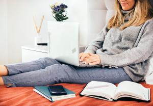 a woman sitting on the floor with a laptop and books at River View Boutique Apts in Ayia Napa
