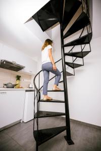 a woman standing on a spiral staircase in a kitchen at River View Boutique Apts in Ayia Napa