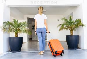 une femme tirant une valise orange dans un aéroport dans l'établissement River View Boutique Apts, à Ayia Napa