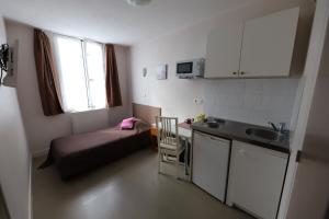 a small room with a bed and a kitchen with a sink at Hôtel du Roussillon in Paris